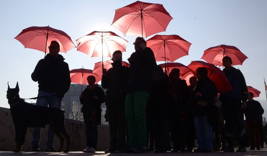 People carrying red umbrellas march through downtown Skopje, Macedonia, marking the International Day to End Violence Against Sex Workers, on Tuesday, Dec. 17, 2013.  A group of sex workers, supported by members of non-government organizations, rallied Tuesday demanding rights for the sex workers and destigmatization of their profession. (AP Photo/Boris Grdanoski/File)