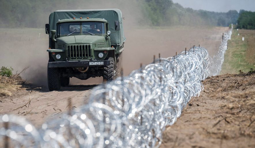 Razor wire marks the border between Hungary and Serbia, but officials are planning to erect a 109-mile-long, 13-foot-tall fence. (Associated Press)