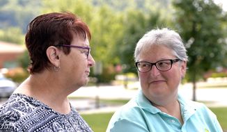 April Miller, right, looks on as her partner Karen Roberts as she addresses the media outside the Rowan County courthouse in Morehead, Ky., Thursday, Aug. 13, 2015. Miller and Roberts, two of the original plaintiffs in the federal suit against Rowan County, Ky., and Rowan County Clerk Kim Davis were at the courthouse to apply for their marriage license following U.S. District Judge David Bunning&#39;s decision Wednesday ordering Davis to begin issuing marriage licenses. (AP Photo/Timothy D. Easley)