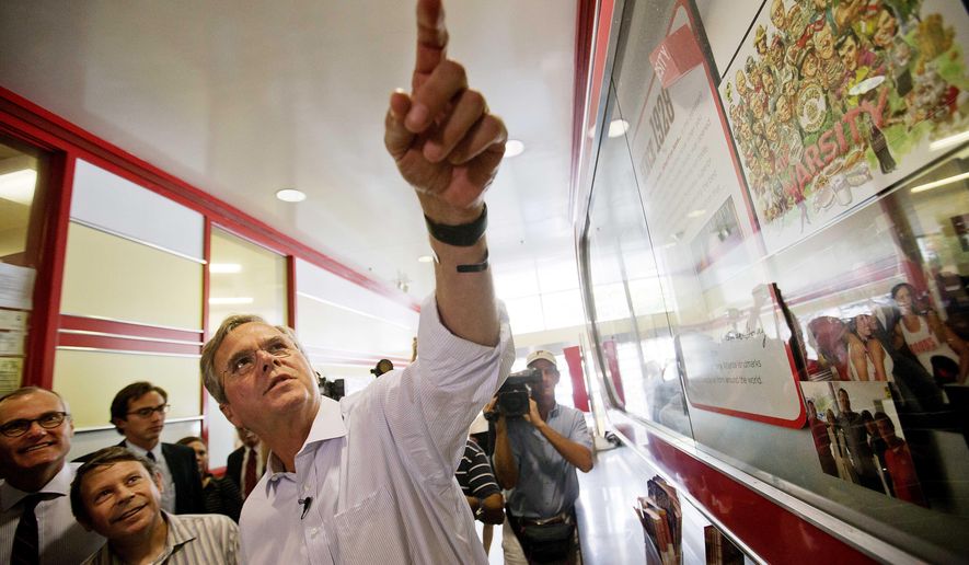 Republican presidential candidate, former Florida Gov. Jeb Bush, right, looks up at photos of celebrities who have visited The Varsity as he arrives at the restaurant for a campaign stop Tuesday, Aug. 18, 2015, in Atlanta. (AP Photo/David Goldman)