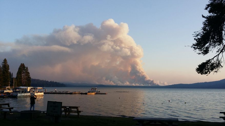 In this photo taken Wednesday, Aug. 19, 2015, smoke from the National Creek Complex fire rises above the horizon across Diamond Lake, Ore., in this view from the Diamond Lake Resort. The wildfire, located between Diamond Lake and Crater Lake in southern Oregon, has forced the closure of the north entrance to Crater Lake, but other parts of Crater Lake Park National Park remain open and the Diamond Lake Resort is still in operation. (AP Photo/John H. Jonesburg III) MANDATORY CREDIT