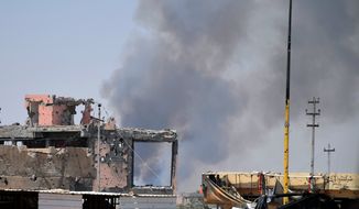 Smoke rises above a damaged building following a U.S.-led coalition airstrike against Islamic State group positions during a military operation to regain control of the eastern suburbs of Ramadi, in Anbar province, Iraq, on Aug. 15, 2015. (Associated Press) **FILE**