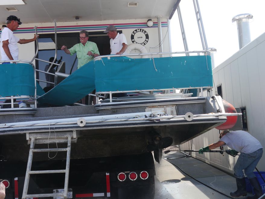 In this photo taken Wednesday, Aug. 19, 2015, Bobby Watkins, center, stands on his boat as it gets decontaminated in Lake Havasu City, Ariz. Lake Havasu State Park opened a decontamination station this week to ensure boats don't spread the invasive quagga mussels. (Zachary Matson/Today's News-Herald via AP)