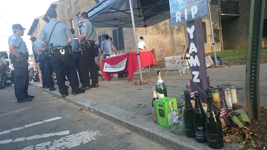 D.C. police officers gather at a community outreach tent placed in the Shaw neighborhood on Aug. 21. The tent, meant to foster community interaction, was placed next to a shrine erected for Tamara Gliss, who was fatally shot at a Memorial Day barbecue when someone fired shots into a crowd. (Andrea Noble/The Washington Times)
