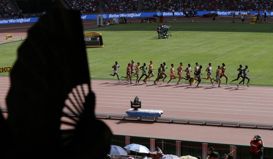 A spectator fans them self as competitors ran past in a men’s 5000m round one heat at the World Athletics Championships at the Bird&#39;s Nest stadium in Beijing, Wednesday, Aug. 26, 2015. (AP Photo/Kin Cheung)