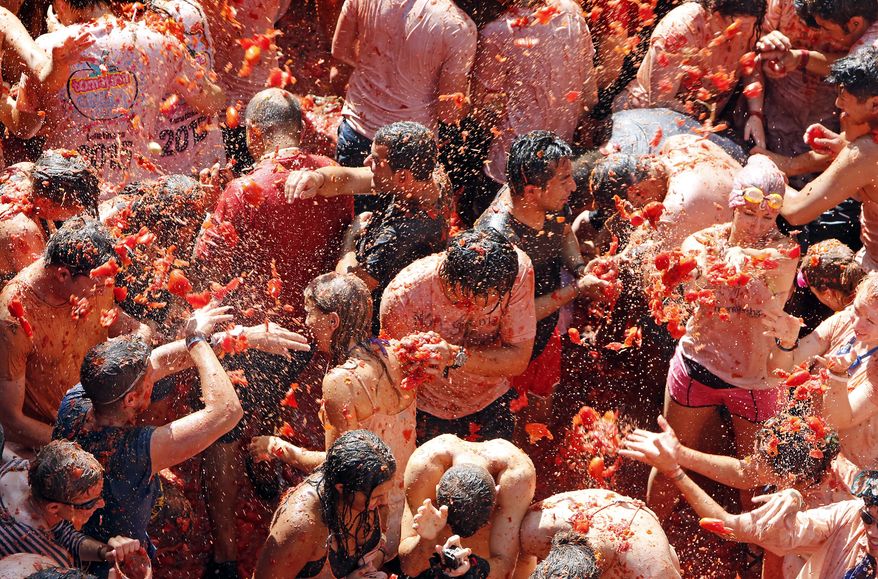 Crowds of people throw tomatoes at each other, during the annual "tomatina" tomato fight fiesta, in the village of Bunol, 50 kilometers outside Valencia, Spain, Wednesday, Aug. 26, 2015. (AP Photo/Alberto Saiz)