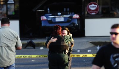 A Sunset Police officer (right) and another law enforcement officer embrace in front of the Sunset Mini Mart on Wednesday in Sunset, La. (Associated Press)