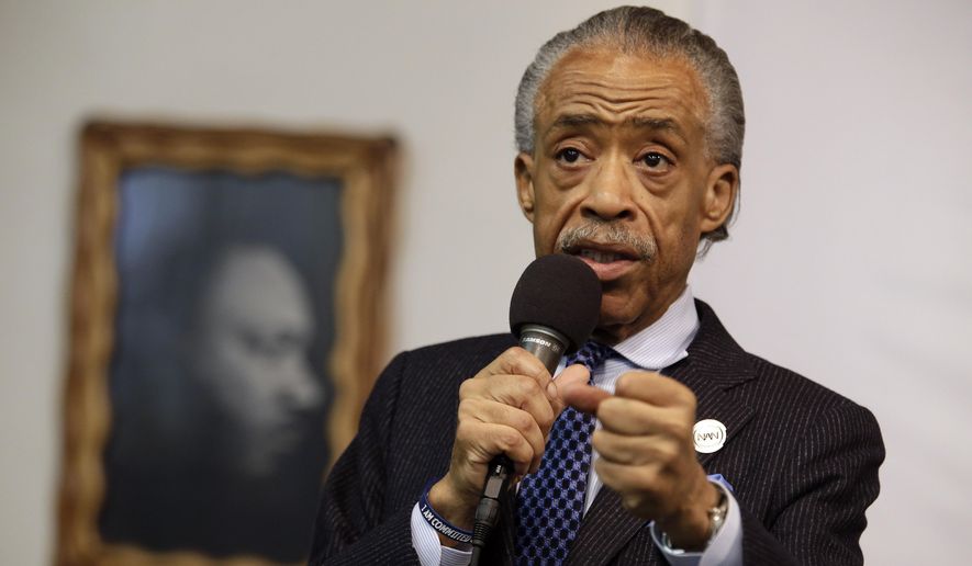In this May 2, 2015, file photo, a portrait of the Rev. Dr. Martin Luther King Jr. hangs on the wall behind the Rev. Al Sharpton as he speaks during a rally at the National Action Network, in New York. (AP Photo/Mary Altaffer, File)