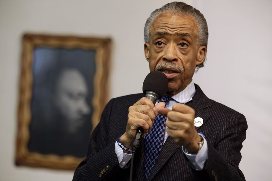 In this May 2, 2015, file photo, a portrait of the Rev. Dr. Martin Luther King Jr. hangs on the wall behind the Rev. Al Sharpton as he speaks during a rally at the National Action Network, in New York. (AP Photo/Mary Altaffer, File)