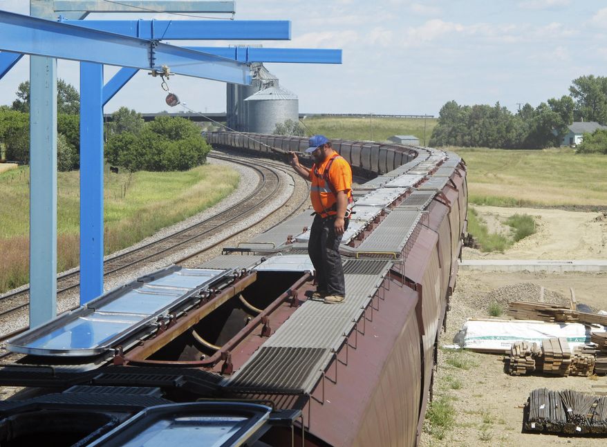 In this Aug. 20, 2015 photo, elevator worker Brian Grahn inspects a rail car about to be loaded with spring wheat in Sterling, N.D. With fall harvest fast approaching, farmers are expecting to get the trains they need to move crops to market, a turnaround from the past two years when elevators across North Dakota _ and in some other farm states _ were overflowing and mountains of grain were piled on the ground awaiting rail cars. (AP Photo/James MacPherson)