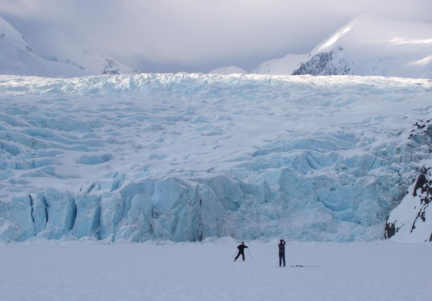 In this March 29, 2006 photo, a skier poses for a photograph on Portage Lake in front of Portage Glacier, about 50 miles south of Anchorage, Alaska. The Portage Glacier, which is a major Alaska tourist destination near Anchorage has retreated so far it no longer can be seen from a multimillion-dollar visitors center built in 1986. President Obama leaves Monday, Aug. 31, 2015 for a three-day visit to the 49th state in which he will speak at a State Department climate change conference and become the first president to visit the Alaska Arctic. There and even in the sub-Arctic part of the state, he will see the damage caused by warming, damage that has been evident to scientists for years. (Evan R. Steinhauser/Anchorage Dispatch News via AP, File)