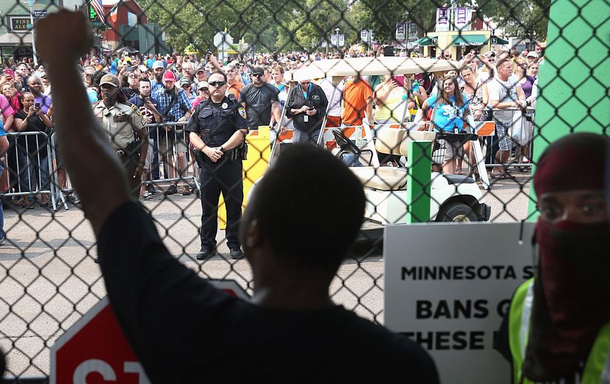 Black Lives Matter protesters agitate at the front gate of the Minnesota State Fair during a protest Saturday. Some fear the protest movement may be promoting violence against police that contributed to a Houston deputy&#39;s slaying by a black man Friday. (Star Tribune via Associated Press)