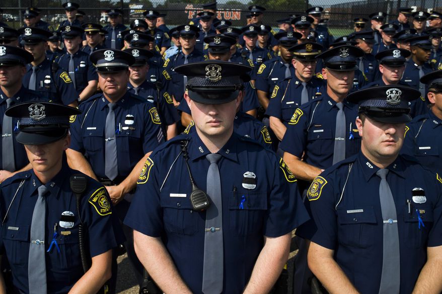 Law enforcement personnel stand row by row outside of Fenton High School, Tuesday, Sept. 1, 2015, for the funeral of Michigan State Police trooper Chad Wolf in Fenton, Mich. The 38-year-old Wolf died Friday, hours after he was struck by a car hauling a trailer and dragged for miles in northern Oakland County. He had been a trooper since 2008. (Jake May/The Flint Journal-MLive.com via AP) LOCAL TELEVISION OUT; LOCAL INTERNET OUT; MANDATORY CREDIT
