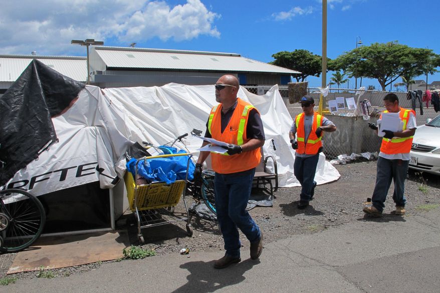 Honolulu Department of Facility Maintenance crews post signs at the Kakaako homeless encampment in Honolulu on Tuesday, Sept. 1, 2015. The signs posted on the outer streets of the Kakaako encampment say authorities will enforce rules next week that prohibit leaving personal property on sidewalks. (AP Photo/Cathy Bussewitz)