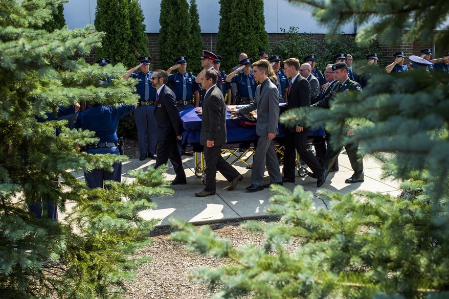 Michigan State Police troopers stand at attention as pallbearers ferry the casket of Michigan State Police trooper Chad Wolf to a hearse outside Fenton High School during a funeral, Tuesday, Sept. 1, 2015, in Fenton, Mich. The 38-year-old Wolf died Friday, hours after he was struck by a car hauling a trailer and dragged for miles in northern Oakland County. He had been a trooper since 2008. (Jake May/The Flint Journal-MLive.com via AP) LOCAL TELEVISION OUT; LOCAL INTERNET OUT; MANDATORY CREDIT