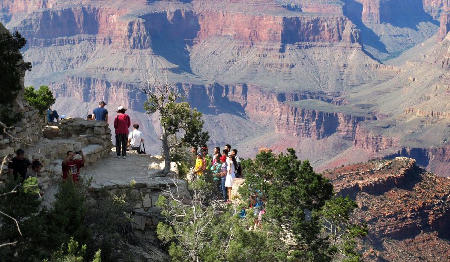 In this Wednesday, Aug. 19, 2015 photo, visitors gather at an outlook on the South Rim of Grand Canyon National Park in northern Arizona. The Grand Canyon and other big national parks are seeing more visitors than usual this year, partly driven by good weather, cheap gas and marketing campaigns. (AP Photo/Felicia Fonseca)