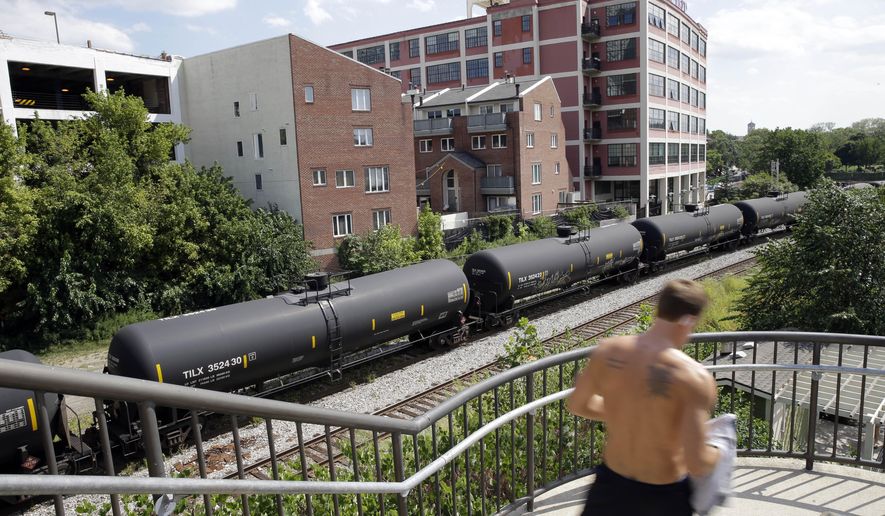 A man walks past homes, condominiums, and train tank cars with signs indicating petroleum crude oil standing idle on the tracks in Philadelphia on Wednesday, Aug. 26, 2015. Activists in Philadelphia question whether the city has adequately communicated its evacuation plans with residents who would have to leave quickly after an accident. (AP Photo/Matt Rourke)