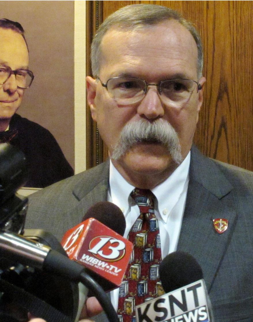 Kansas Supreme Court Chief Justice Lawton Nuss answers questions from reporters in the lobby in the Kansas Judicial Center featuring portraits of past appellate court judges, Thursday, Sept. 3, 2015, in Topeka, Kan. Nuss says the justices might review a lawsuit involving the court's power even though they arguably have a conflict of interest. (AP Photo/John Hanna)