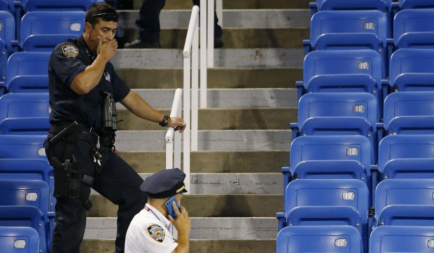 Police officers investigate the southwest corner of Louis Armstrong Stadium after a drone flew over the court, buzzing the players during a match between Flavia Pennetta, of Italy, and Monica Niculescu, of Romania, during the second round of the U.S. Open tennis tournament in New York, Thursday, Sept. 3, 2015. The drone crashed into the seats and can be seen to the right of the police officer on his phone. (AP Photo/Kathy Willens)