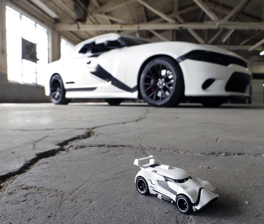 A Star Wars decorated Dodge Charger modeled after a First Order Stormtrooper Car is seen near a First Order Stormtrooper Car toy in a warehouse Thursday, Sept. 3, 2015, in Paterson, N.J. Inspired by the film Star Wars, Hot Wheels is taking over New York City on "Force Friday" Sept. 4 with a fleet of Stormtrooper vehicles. (AP Photo/Mel Evans)