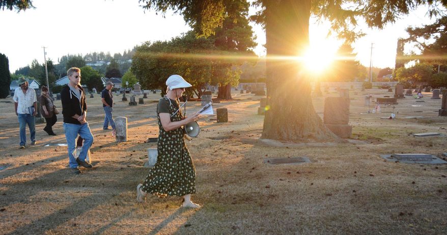 ADVANCE FOR USE MONDAY, SEPT. 7 - In this photo taken Aug. 18, 2015, “The Silent Stones Speak” tour guide Margie Wilson, of the Burlington Historical Society guides the participants through the Green Hills Cemetary in Burlington, Wash., in search of unique headstones that offer symbols and shapes for interpretation. (Brandy Shreve/Skagit Valley Herald via AP) MANDATORY CREDIT