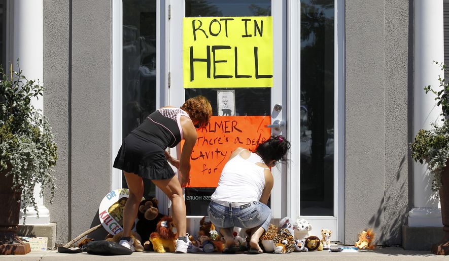 Women place a sign outside Dr. Walter James Palmer&#39;s dental office in Bloomington, Minn., on July 29, 2015. Mr. Palmer reportedly paid $50,000 to track and kill Cecil, a black-maned lion, just outside Hwange National Park in Zimbabwe. (Associated Press)