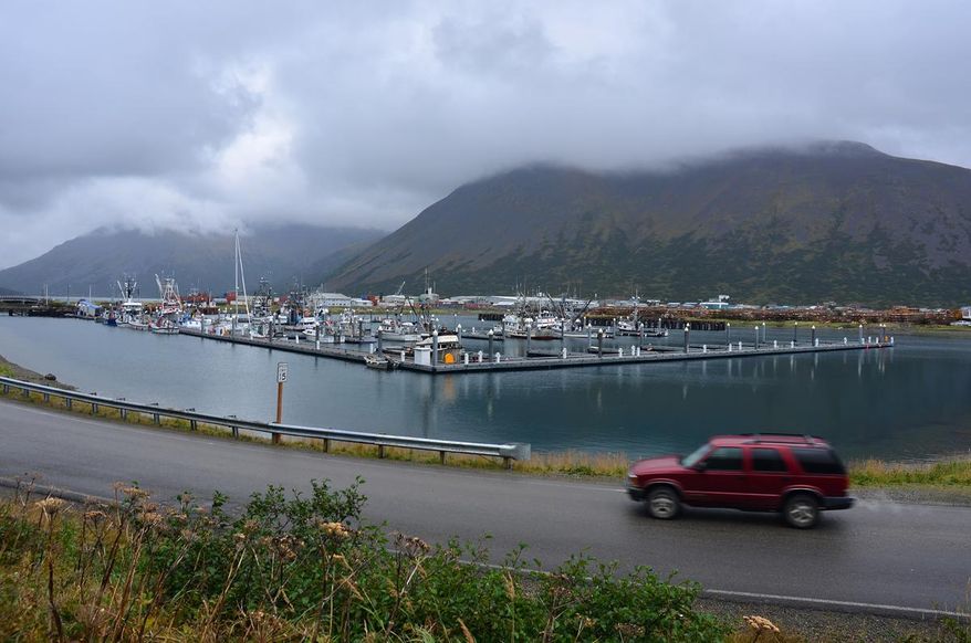In this photo taken Sept. 23, 2013, a driver passes the small boat harbor in King Cove, Alaska. A federal judge in Alaska on Tuesday, Sept. 8, 2015, dismissed a lawsuit brought over the U.S. Interior Department's refusal to allow for a road from King Cove to an all-weather airport at Cold Bay. The road has drawn opposition from environmental groups because it would run through Izembek National Wildlife Refuge. (James Brooks(/Kodiak Daily Mirror via AP) MANDATORY CREDIT