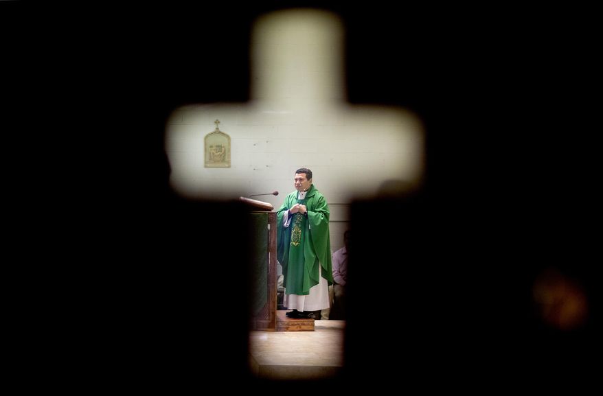 ADVANCE FOR USE THURSDAY, SEPT. 10, 2015 AND THEREAFTER - The Rev. William Canales is seen through a window of a door while leading Mass at St. John Paul II Pastoral Center in Gainesville, Ga., on Sunday, Aug. 9, 2015. This mission, in the Archdiocese of Atlanta, was built in a hurry, to serve the many Latinos who labor at the poultry processing plants that form the economic backbone of Gainesville. (AP Photo/David Goldman)