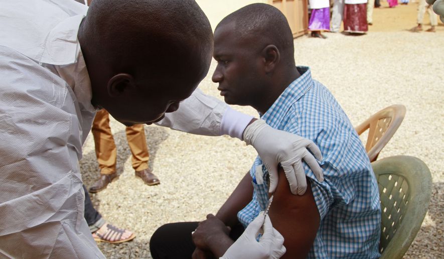 A health worker injects a man with an Ebola vaccine in Conakry, Guinea, on March 7. (Associated Press)