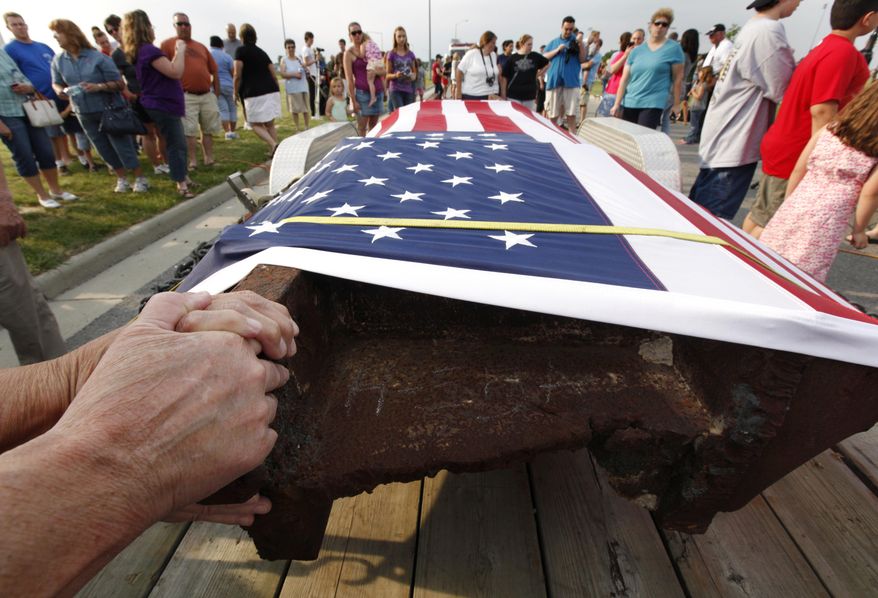 FILE - In this June 17, 2011, file photo, people touch a 12-foot steel beam from the World Trade Center during the beam's arrival from New York City in Wauseon, Ohio. Pieces of steel from the twin towers have been parceled out to all 50 states and eight countries for memorials and museum exhibits and were used in the construction of the U.S. Navy ship USS New York. Of 2,200 pieces of steel preserved in an airplane hangar in New York City, there are fewer than 30 left. (AP Photo/Paul Sancya, File)