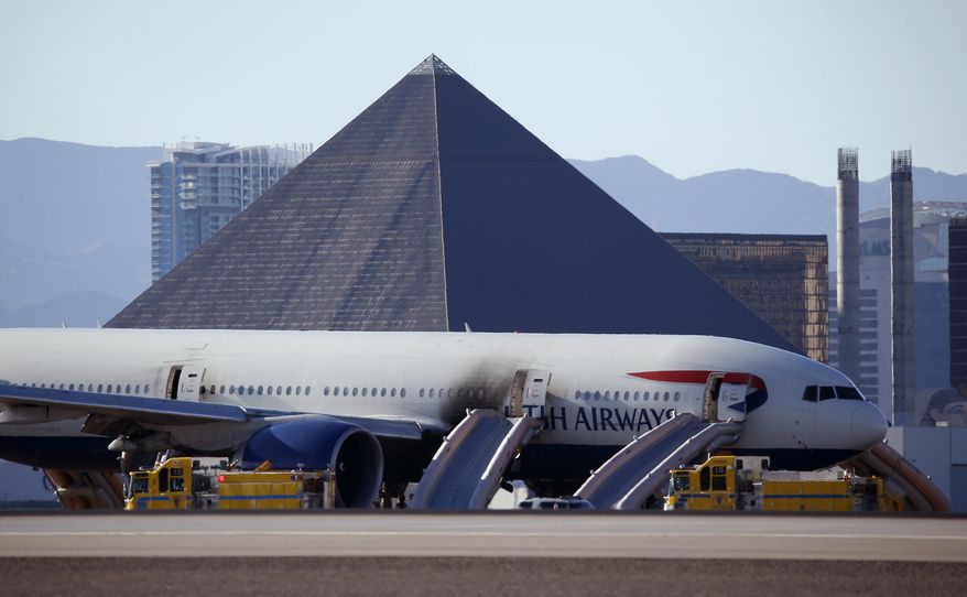 Casinos along the Las Vegas Strip can be seen behind a plane that caught fire at McCarren International Airport, Tuesday, Sept. 8, 2015, in Las Vegas. An engine on the British Airways plane caught fire before takeoff. (AP Photo/John Locher)