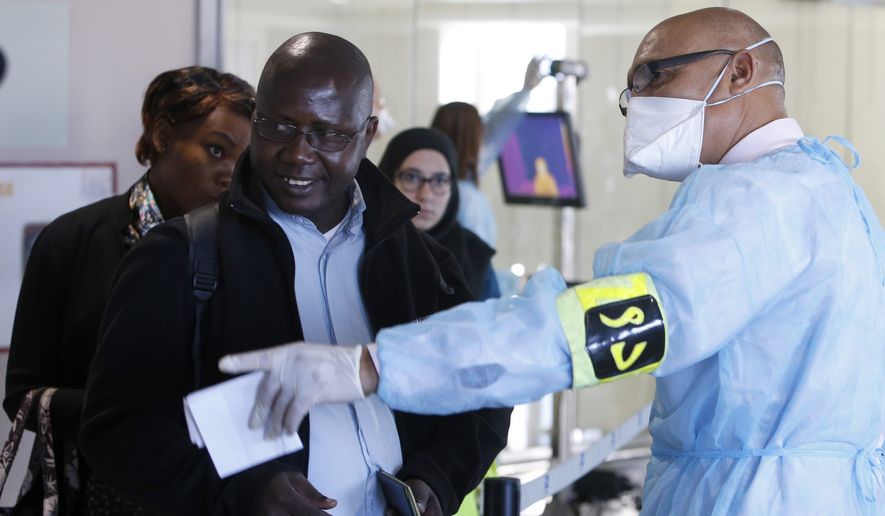 A worker from a Moroccan health screening team dressed in protective gear directs passengers at the arrivals hall of the Mohammed V airport in Casablanca on Oct 9. (Associated Press)
