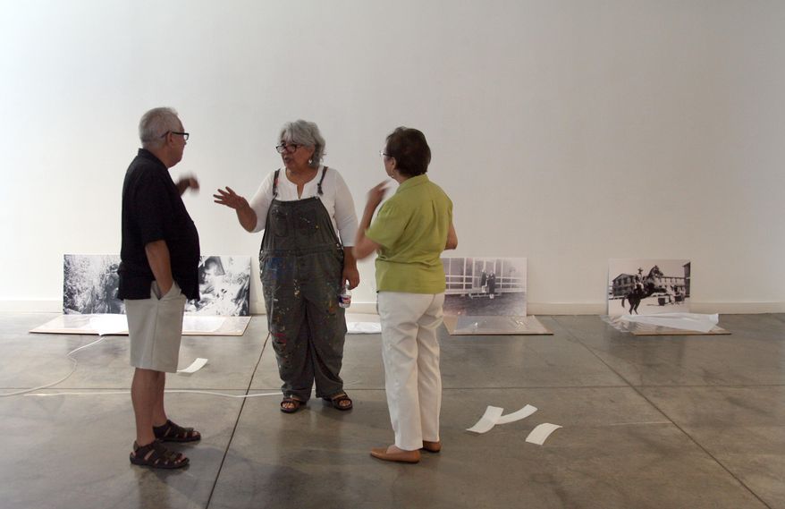 Viola Delgado, center, who's curating the exhibit, speaks with Albert Valtierra and Rosemary Hinojosa, at the Latino Cultural Center while working on the show that'll open there on September 11th, in Dallas on Saturday, Sept. 5, 2015. (Guy Reynolds/The Dallas Morning News via AP) MANDATORY CREDIT; MAGS OUT; TV OUT; INTERNET USE BY AP MEMBERS ONLY; NO SALES