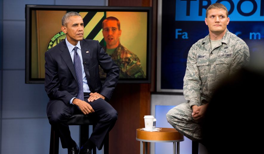 President Barack Obama, accompanied by Tech Sgt. Nathan Parry, right, takes a question from a service member in Afghanistan, on screen at center, during a town hall with service members at Fort Meade, Md., Friday, Sept. 11, 2015, on the 14th anniversary of the 9/11 attacks. (AP Photo/Andrew Harnik)