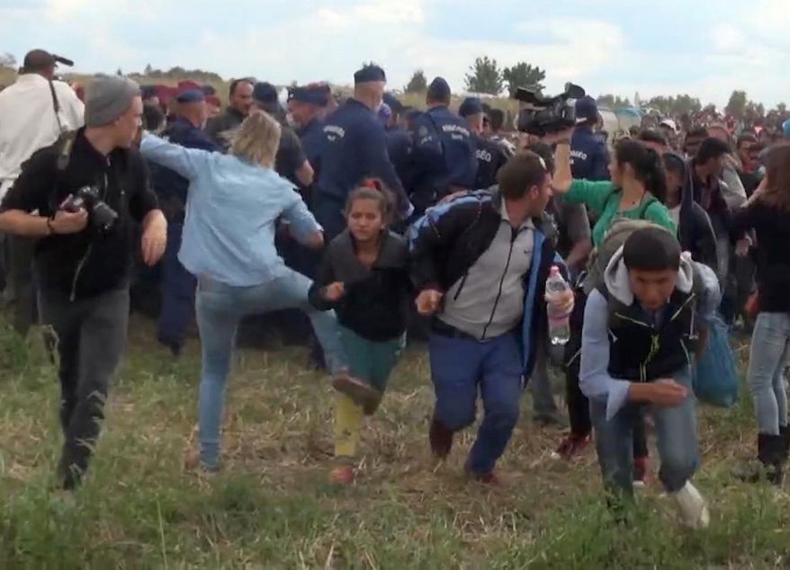 In this image taken from TV a Hungarian camerawoman, center left in blue, kicks out at a young migrant who had just crossed the border from Serbia near Roszke Hungary Tuesday, Sept. 8, 2015. The camerawoman has been fired after she was caught on video kicking and tripping migrants entering Hungary across the border with Serbia. (Index.Hu. via AP)
