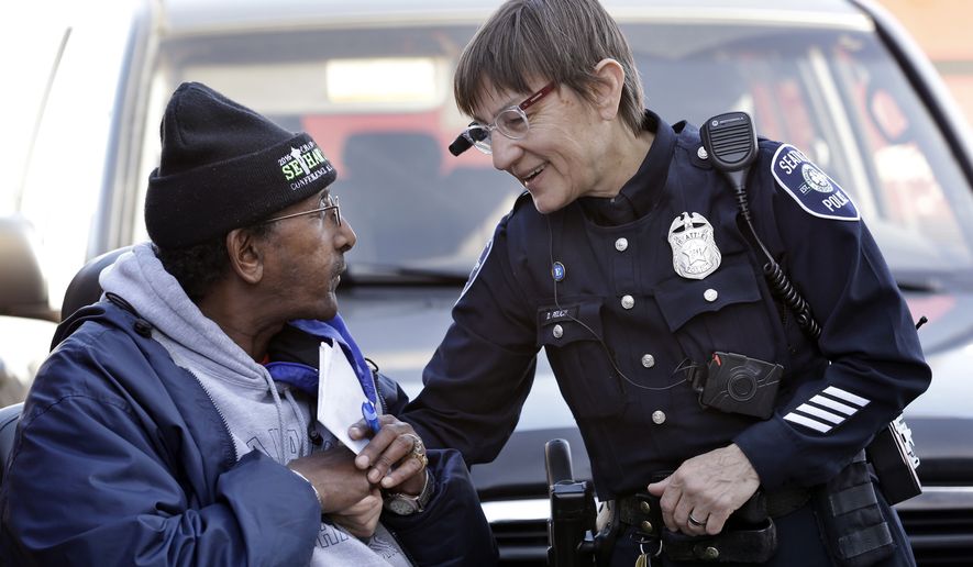 Seattle police officer Debra Pelich, right, wears a video camera on her eyeglasses as she talks with Alex Legesse before a small community gathering in Seattle, in this March 12, 2015, file photo. The camera is attached to a battery pack and controls on the officer's uniform. (AP Photo/Elaine Thompson, File)