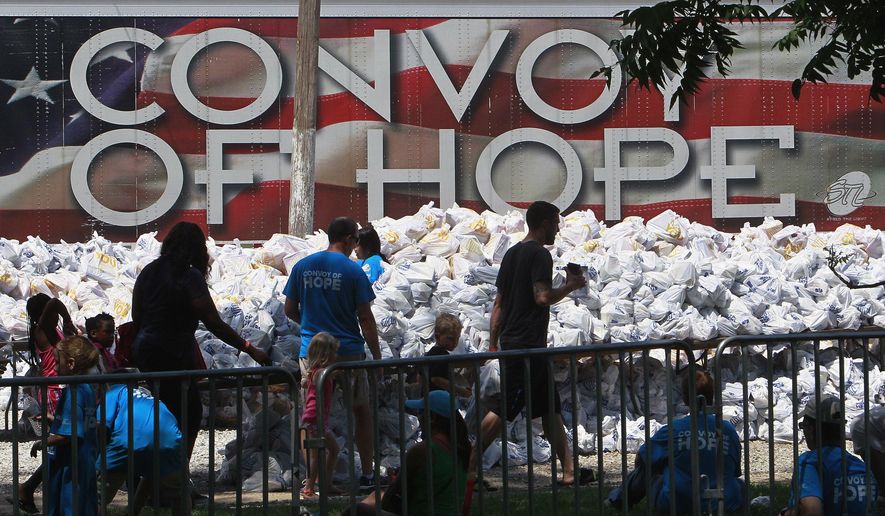 In this Aug. 15, 2015, file photo, volunteers and patrons of a Convoy of Hope event walk past bagged groceries as they exit a park in O’Fallon, Ill. Convoy of Hope, based in Springfield, Mo., is an interdenominational organization that provides assistance to those in need. (Tim Vizer/Belleville News-Democrat via AP) ** FILE **
