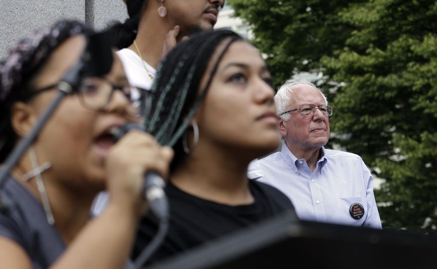 FILE - In this Aug. 8, 2015 file photo, Democratic presidential candidate Sen. Bernie Sanders, I-Vt. listens at right as Marissa Johnson speaks at left, accompanied by Mara Jacqueline Willaford, as the two women take over the microphone at a rally in downtown Seattle. The women, co-founders of the Seattle chapter of Black Lives Matter, took over the microphone moments after Sanders began speaking and refused to relinquish it. Sanders eventually left the stage without speaking further and instead waded into the crowd to greet supporters. Rising in political polls, Bernie Sanders is trying to overcome hurdles among black voters who are still learning about him and could help determine whether his insurgent campaign can last. (AP Photo/Elaine Thompson, File)