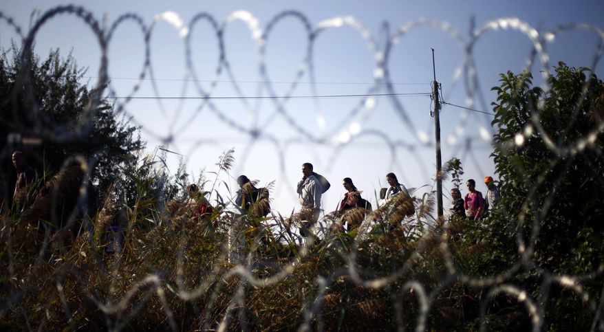 Migrants arrive at the border line between Serbia and Hungary near Roszke, southern Hungary, Sunday, Sept. 13, 2015. Hundreds of thousands of Syrian refugees and others are still making their way slowly across Europe, seeking shelter where they can, taking a bus or a train where one is available, walking where it isn't. The latest string of walkers made their way Friday from the Hungarian border across Austria toward the capital, Vienna. (AP Photo/Matthias Schrader)