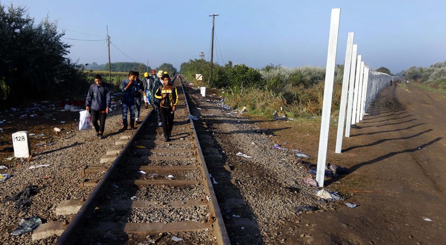 Migrants cross the border line between Serbia and Hungary near Roszke, southern Hungary, Sunday, Sept. 13, 2015. Hundreds of thousands of Syrian refugees and others are still making their way slowly across Europe, seeking shelter where they can, taking a bus or a train where one is available, walking where it isn't. The latest string of walkers made their way Friday from the Hungarian border across Austria toward the capital, Vienna. (AP Photo/Matthias Schrader)