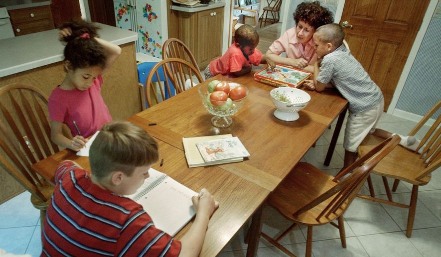 Diane Toler, director of the Catholic Homeschoolers of New Jersey, plays a game to help improve the math skills of her sons, John, 6, (right) and Michael, 4, as another son, Joshua, 10, left, and daughter, Alexandra, 8, work on a writing assignment at their home in Cherry Hill, N.J. (Associated Press)
