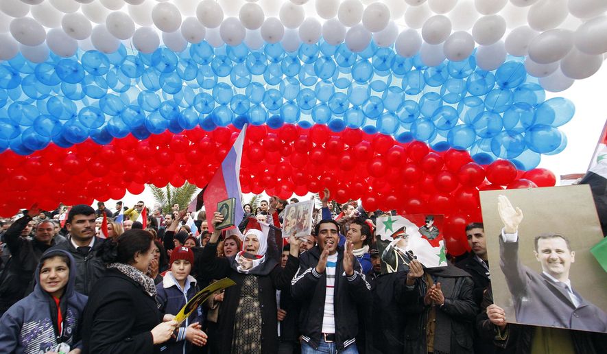 FILE - In this Feb. 7, 2012, file photo, pro-Syrian government protesters gather under a large Russian flag made with balloons as they cheer a convoy believed to be transporting Russian Foreign Minister Sergey Lavrov in Damascus, Syria. In ramping up its military involvement in Syria's civil war, Russia appears to be betting that the West, horrified by Islamic State's atrocities, may be willing to tolerate Syrian President Bashar Assad for a while, perhaps as part of a transition. (AP Photo/Muzaffar Salman, File)