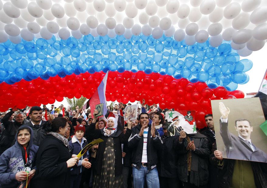 FILE - In this Feb. 7, 2012, file photo, pro-Syrian government protesters gather under a large Russian flag made with balloons as they cheer a convoy believed to be transporting Russian Foreign Minister Sergey Lavrov in Damascus, Syria. In ramping up its military involvement in Syria's civil war, Russia appears to be betting that the West, horrified by Islamic State's atrocities, may be willing to tolerate Syrian President Bashar Assad for a while, perhaps as part of a transition. (AP Photo/Muzaffar Salman, File)