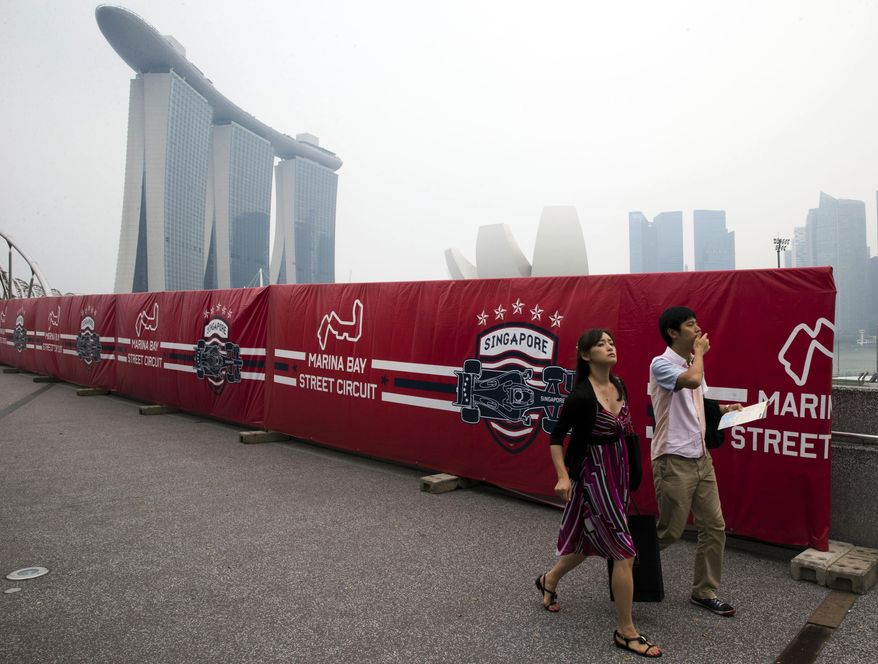Tourists walk past advertisements promoting the upcoming Singapore Formula One Grand Prix on a hazy day in Singapore, Monday, Sept. 14, 2015. Billowing smoke from Indonesian forest fires worsened Singapore&#39;s air pollution, raising concern among organizers of the widely-anticipated F1 night race this weekend, as well as in schools which reopened Monday after a weeklong term break. (AP Photo/Ng Han Guan)