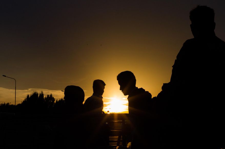 Refugees queue up for a bus, as they arrive at the border between Austria and Hungary, Heiligenkreuz, Austria, late Tuesday Sept. 15, 2015. Austria's Interior Ministry says temporary border controls with Hungary will be in effect immediately after midnight Tuesday. The ministry says the measure could be extended to the country's borders with Slovenia, Italy and Slovakia, if needed. That reflects the possibility that migrants now streaming into Austria from Hungary could instead try to cross into Austria over those borders in large numbers. (AP Photo/Christian Bruna)