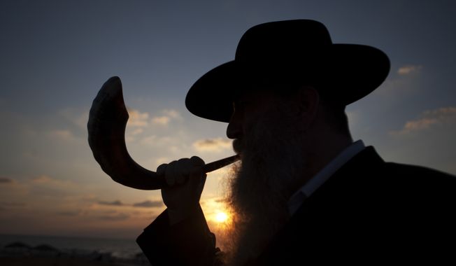 A Jew blows a shofar, ram&#x27;s horn, while others pray as they perform Tasklikh, a Rosh Hashanah ritual for casting sins upon the waters, in front of the Mediterranean sea, in Ashdod, Israel, Thursday, Sept. 29, 2011. Tasklikh is when Jews symbolically throw their sins into moving water during the New Year holiday of Rosh Hashana. (AP Photo/Ariel Schalit)