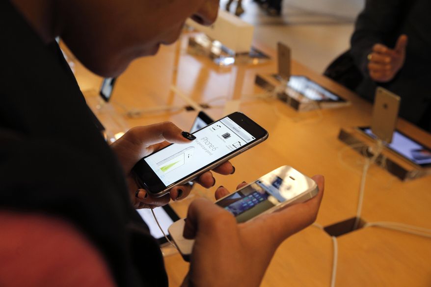 In this Sept. 19, 2014, file photo, a customer checks out the new iPhone 6 at an Apple store in Paris. (AP Photo/Christophe Ena, File)