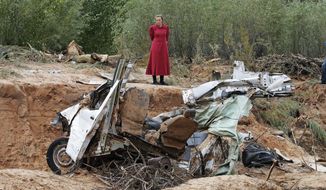 A woman looks at a damaged vehicle swept away during a flash flood Tuesday, Sept. 15, 2015, in Hildale, Utah. The floodwaters swept away vehicles in the Utah-Arizona border town, killing several people. (AP Photo/Rick Bowmer)