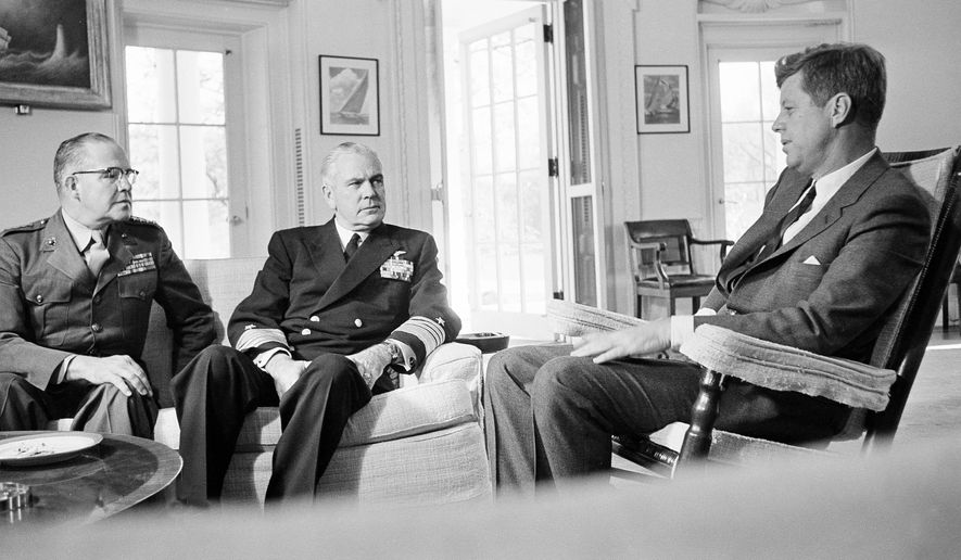 In this Oct. 29, 1962, photo, President John F. Kennedy poses in the White House office with Gen. David Shoup, left, Marine Corps Commandant, and Adm. George Anderson, Chief of U.S. Naval Operations in Washington. The chiefs met with the president to review the situation in Cuba and operation of the U.S. naval blockade.  As the U.S. and Russia reached the brink of nuclear war in 1962, Kennedy received top-secret intelligence from the CIA that a new warhead launcher was spotted in Cuba. That report, given to Kennedy a day before the end of the Cuban Missile Crisis, is among roughly 19,000 pages of newly declassified CIA documents from the Cold War released Wednesday, Sept. 16, 2015. (AP Photo/William J. Smith, File)