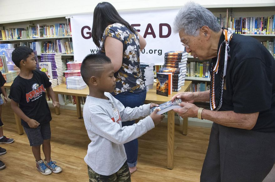 ** ADVANCE FOR SATURDAY SEPT. 19, 2015 AND THEREAFTER ** In this photo taken Sept. 11, 2015, former U.S. Sen. Daniel Akaka hands out free books to student Jeiven-Chase Bachiller at Pohakea School in Ewa district of Honolulu as part of a new youth literacy program. Breaking every library’s rule, dozens of students shouted in the middle of the school's library in early September, but what they shouted would make any librarian’s day. When asked what they wanted to do, they screamed: “Read!” (Craig T. Kojima/Honolulu Star-Advertiser via AP)